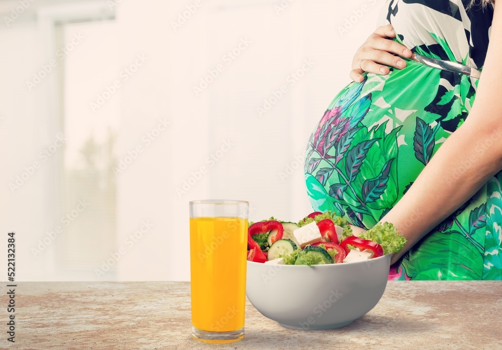 Pregnant woman with fresh salad in bowl. Healthy lunch concept.