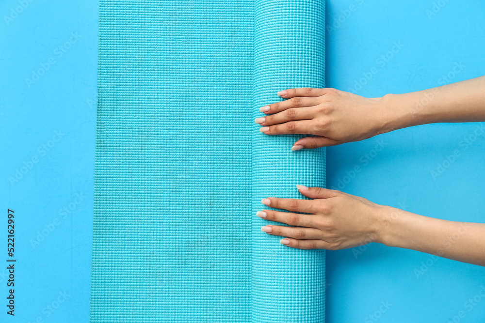 Female hands with yoga mat on color background