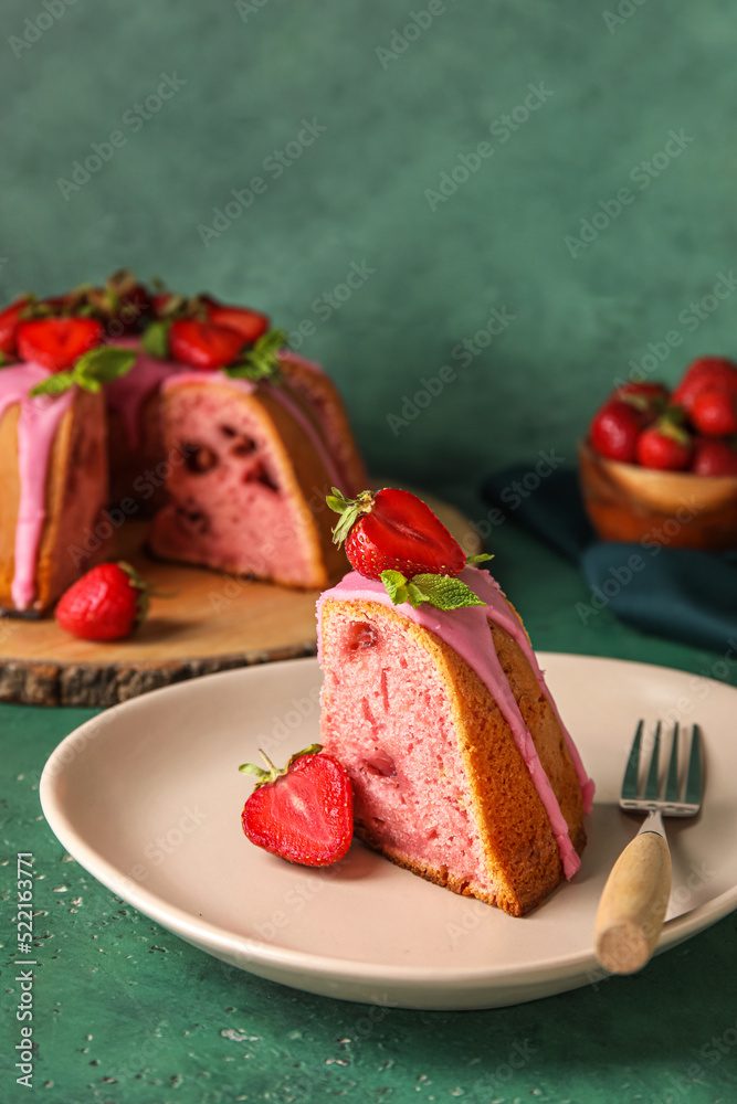 Plate with piece of delicious strawberry cake on green background