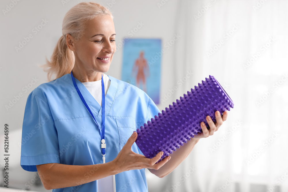 Mature physiotherapist with foam roller in rehabilitation center