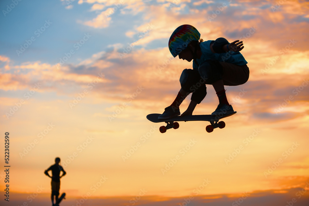 Skateboarder in action. Black silhouette of young boy making air trick with grab on skate in skatepa