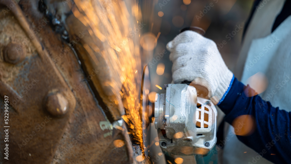 Industrial worker using angel grinder cutting metal, Angel grinder cutting metal with bright sparks,