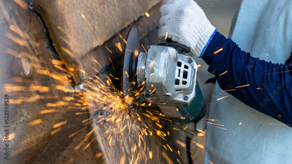 Industrial worker using angel grinder cutting metal, Angel grinder cutting metal with bright sparks,