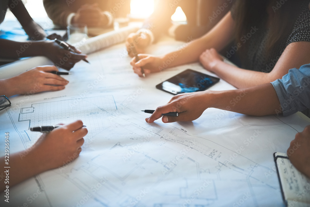 Architect working with a team or group, looking over plans or blueprints and talking about architect