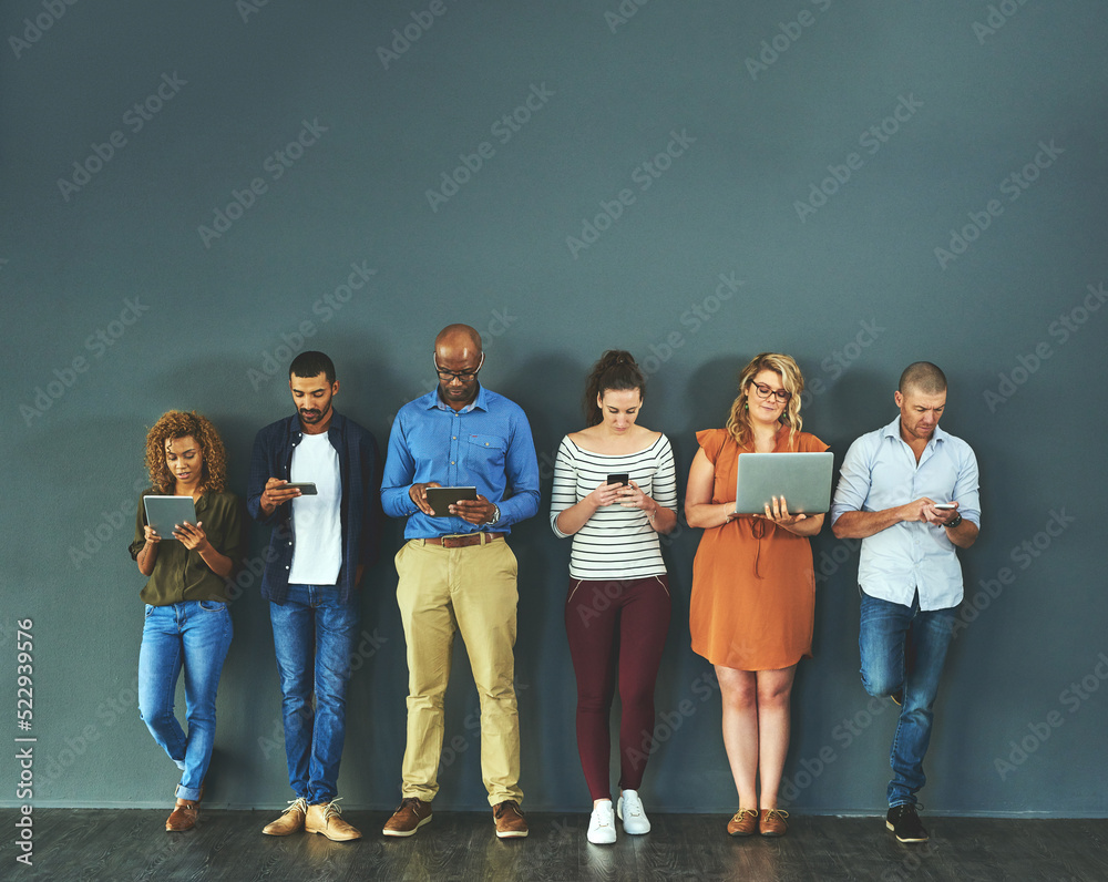 Diverse group of people browsing social media on a phone, tablet and laptop in studio on a grey back