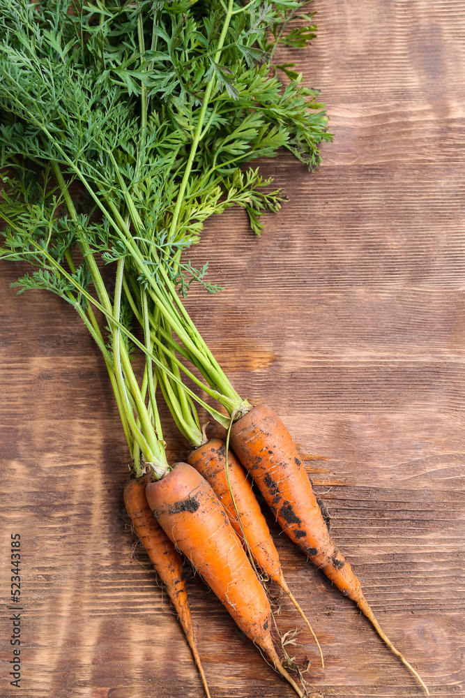 Fresh juicy carrots on wooden background