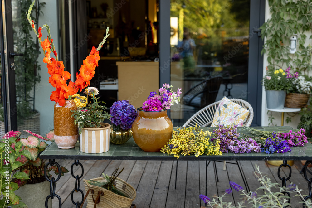 Variety of blooming flowers in vases on table at backyard