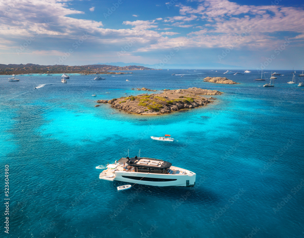 Luxury yacht on blue sea and small island at sunny day in summer. Sardinia, Italy. Aerial view of bo