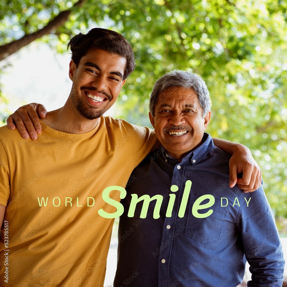 Composition of world smile day text over biracial man and his adult son embracing in garden