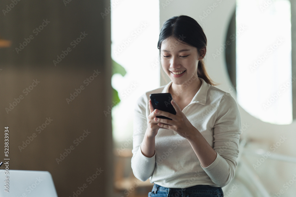 迷人的女人，带着美丽的笑容，在咖啡馆休息时用手机阅读好消息