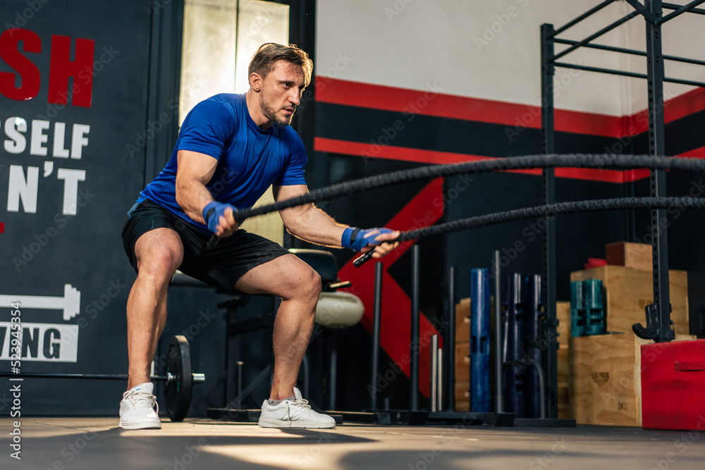 Caucasian active handsome sportsman working out in fitness gym club. 