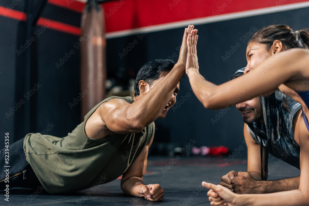 Sportsman and woman high five and encourage each other exercise in gym