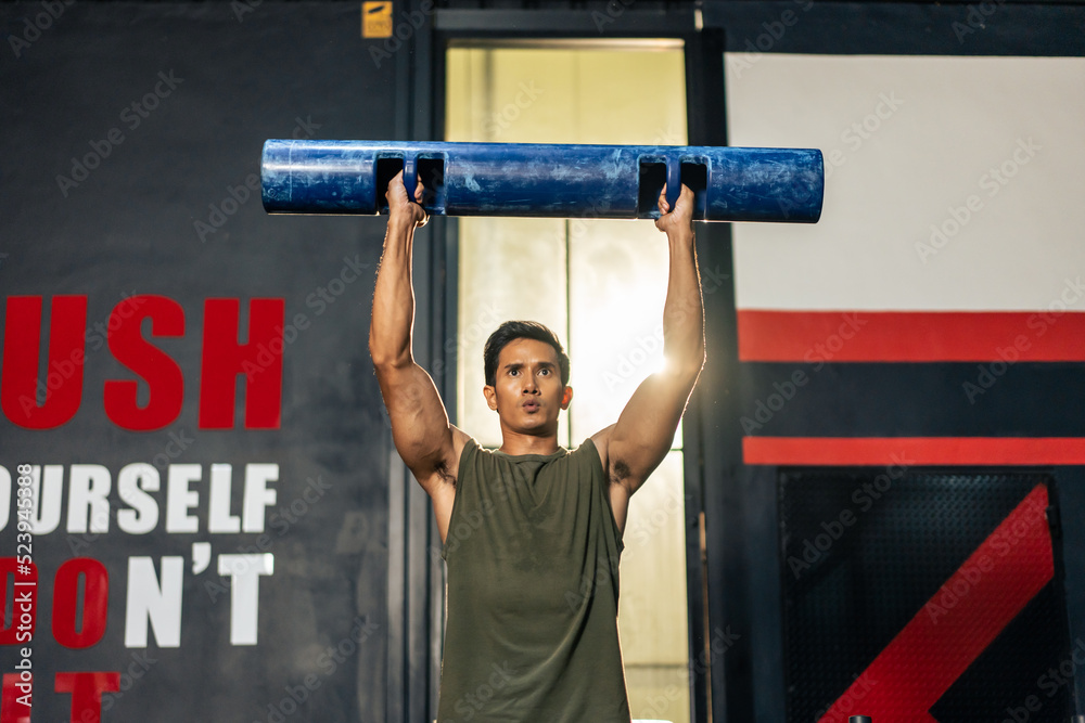 Asian sportsman slowly lifting up weight equipment or barbell in gym