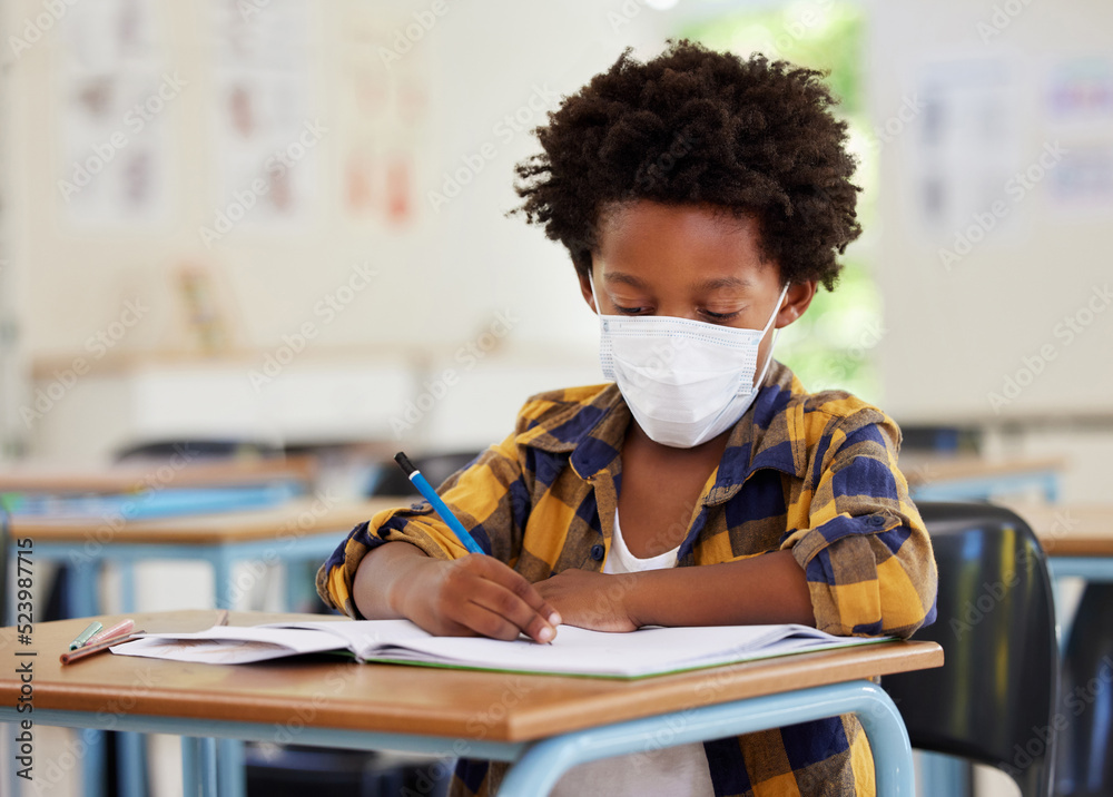 School boy, student and learning while writing and working in his book inside a classroom with a mas