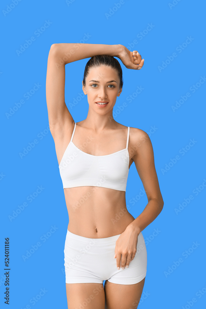 Young tanned woman in underwear on blue background