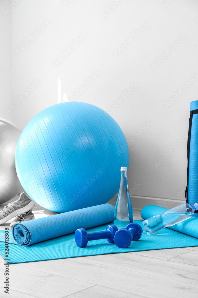 Different sports equipment on floor near white wall