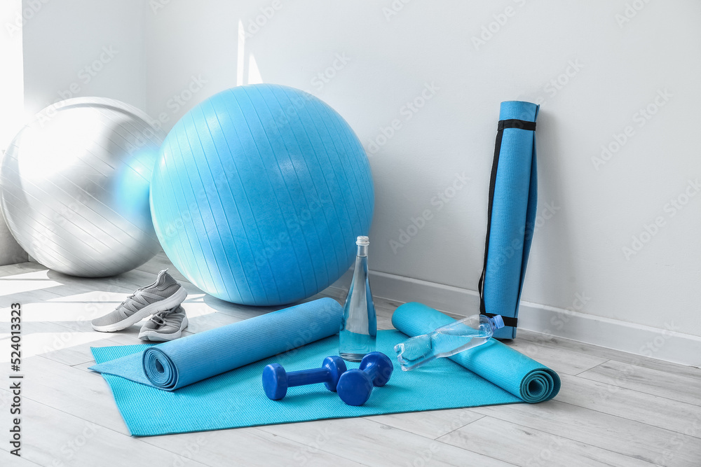 Different sports equipment on floor near white wall