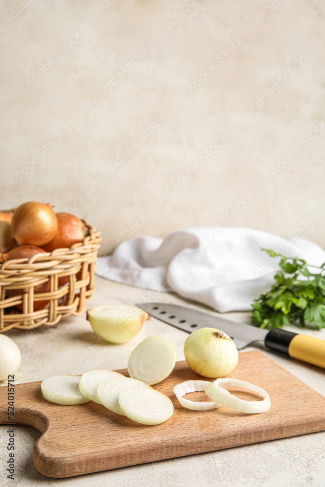 Wooden board with cut onion on light background