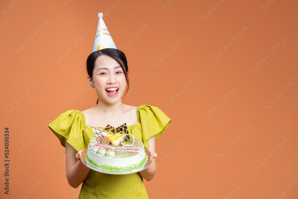 年轻的亚洲女人拿着生日蛋糕