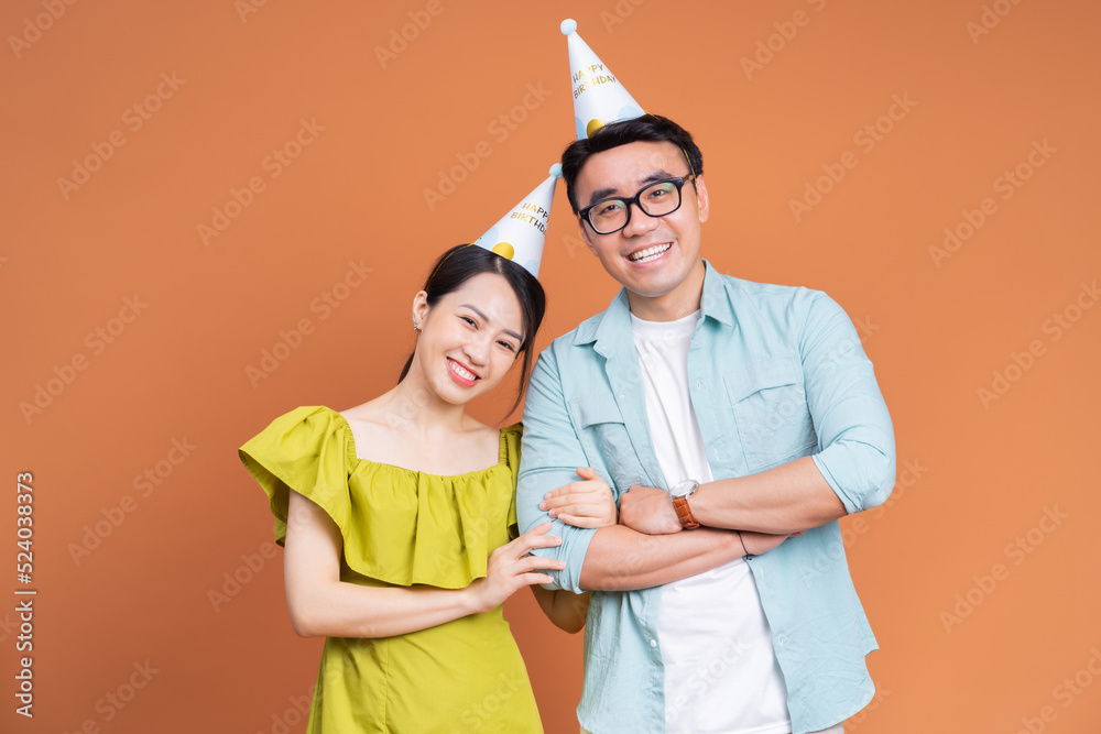 背景是一对年轻的亚洲夫妇拿着生日蛋糕