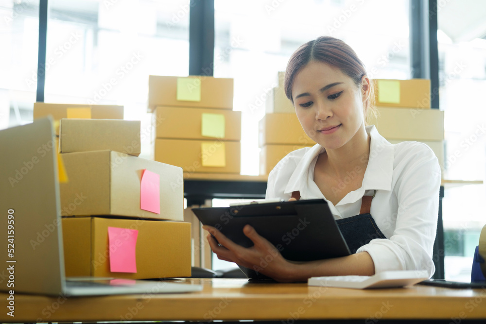 Young asian businesswoman onwer checking parcels list before delivering to customers.