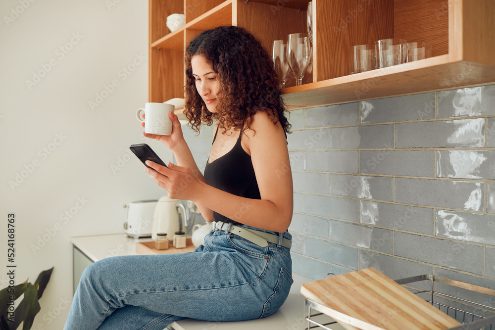 Woman texting, chatting on the phone while relaxed, carefree and sitting on kitchen counter. Young, 