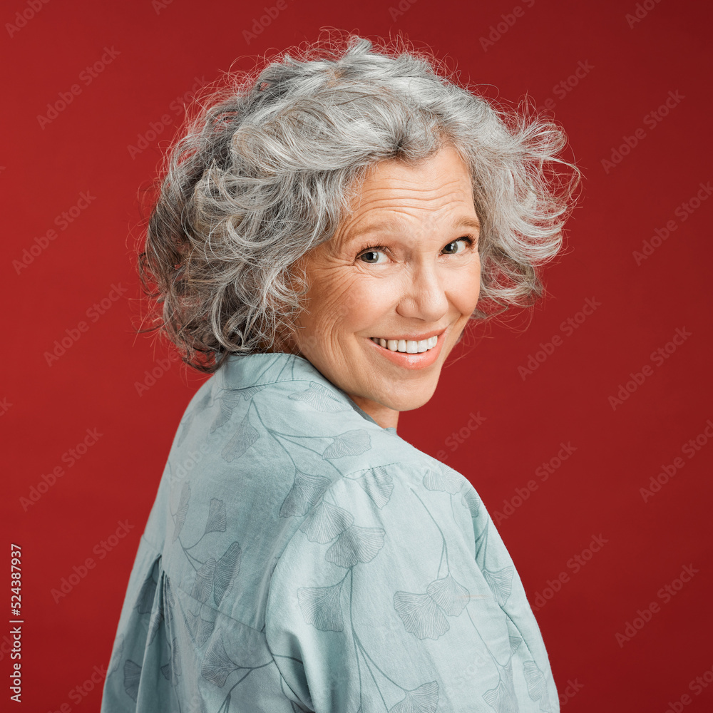 .. Confident, happy and smiling senior woman feeling playful and cheerful while posing against red s