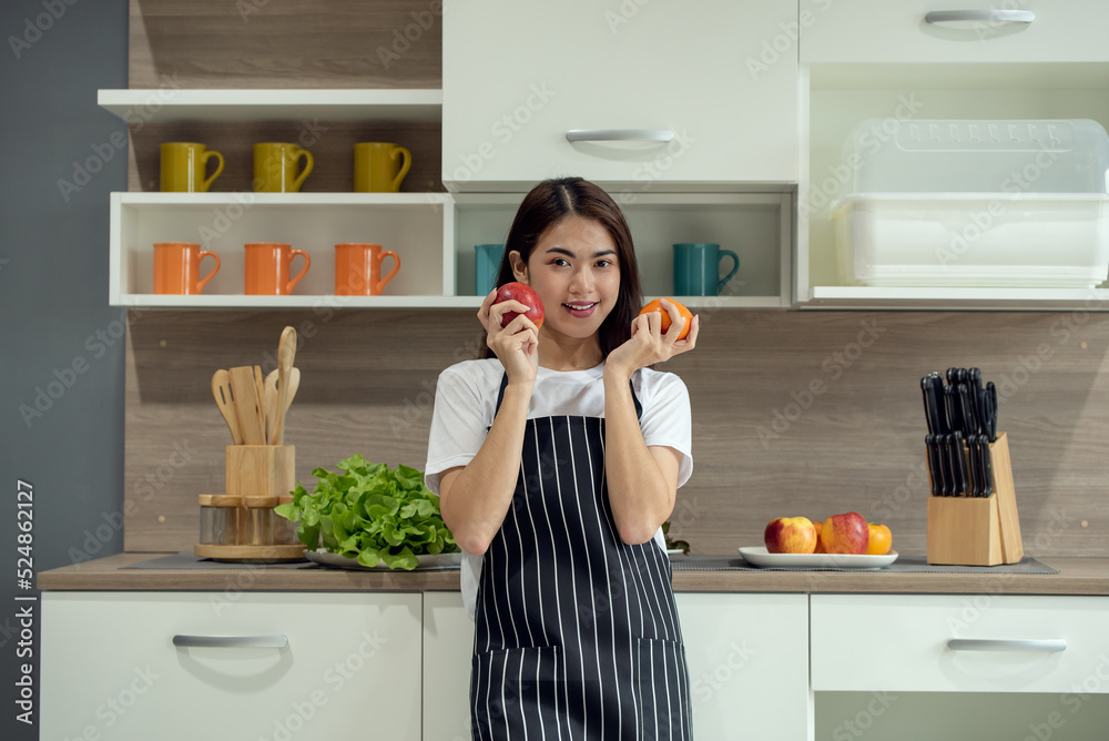 快乐的年轻亚洲女性在现代厨房用新鲜蔬菜和水果烹饪