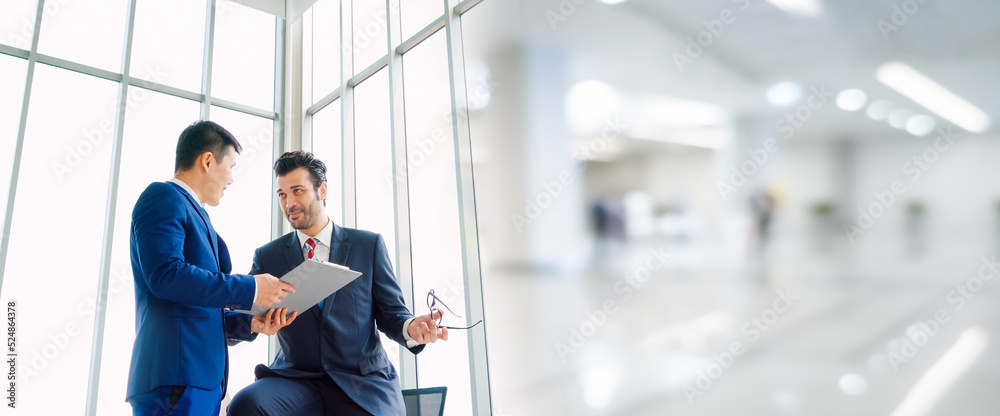 Two business people talk project strategy at office in widen view meeting room. Businessman discuss 