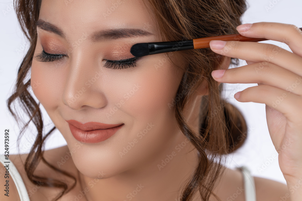 Closeup gorgeous young woman putting black mascara on her long eyelashes with brush. Beauty cosmetic