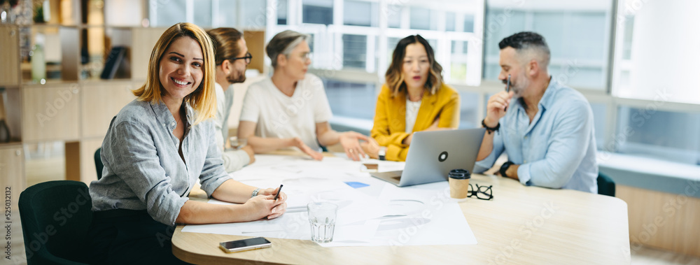 Successful young designer sitting in a meeting with her team