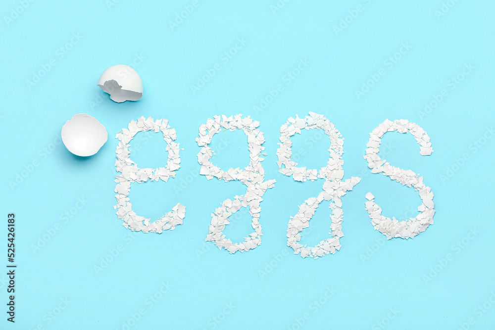 Word EGGS made of broken shells on blue background