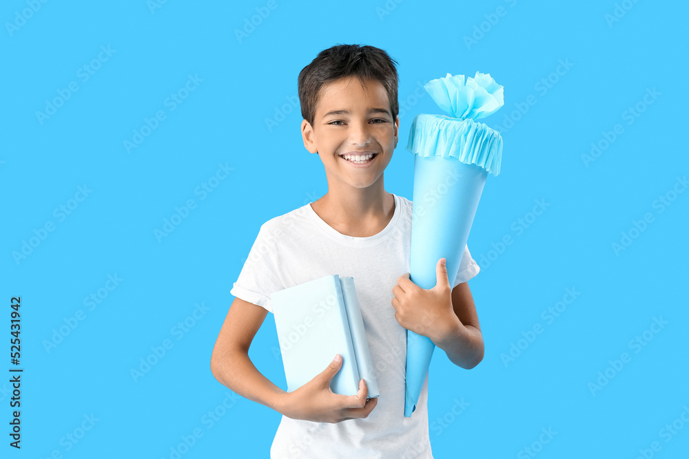 Little boy with school cone and books on blue background