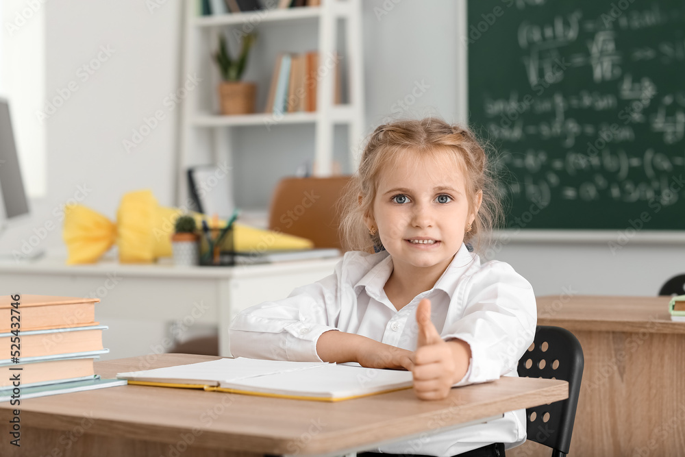 可爱的一年级小学生在教室里对着桌子竖起大拇指