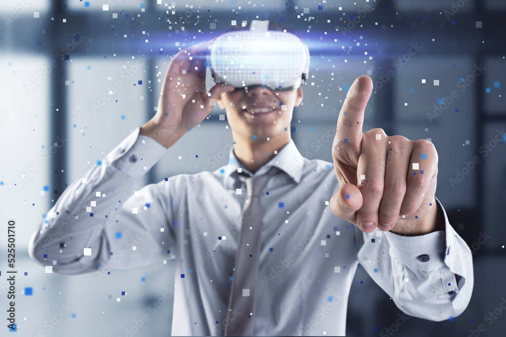 Attractive young european man pointing at abstract hologram with VR glasses in blurry office interio