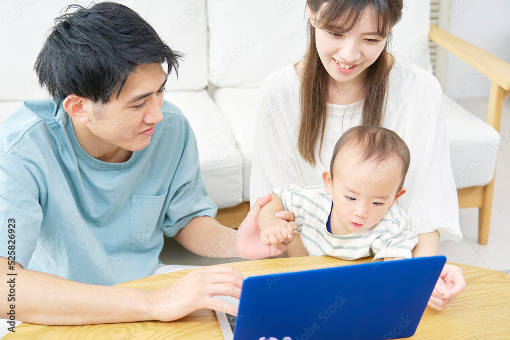 リビングでノートパソコンを見る両親と赤ちゃん