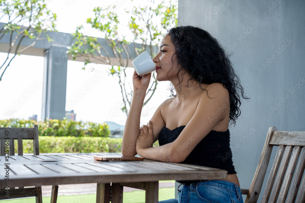 Young woman drinking a cup of coffee with a happy face standing and smiling with a confident smile. 