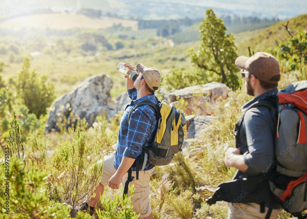 Friends hiking on grass in nature for fitness, wellness and health as thirsty man drinking water and