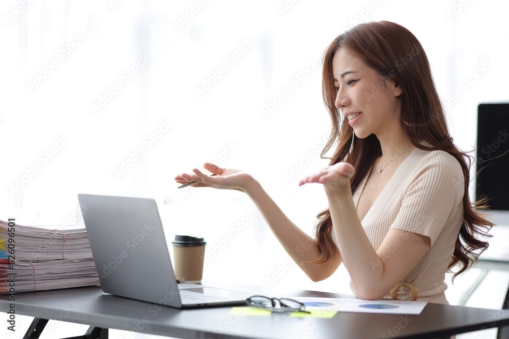 Beautiful Asian businesswoman sitting in her private office, she is talking to her partner via video