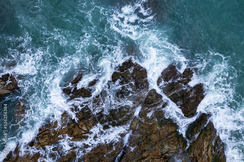 Aerial view Top down seashore big wave crashing on rock cliff Beautiful dark sea surface in sunny da