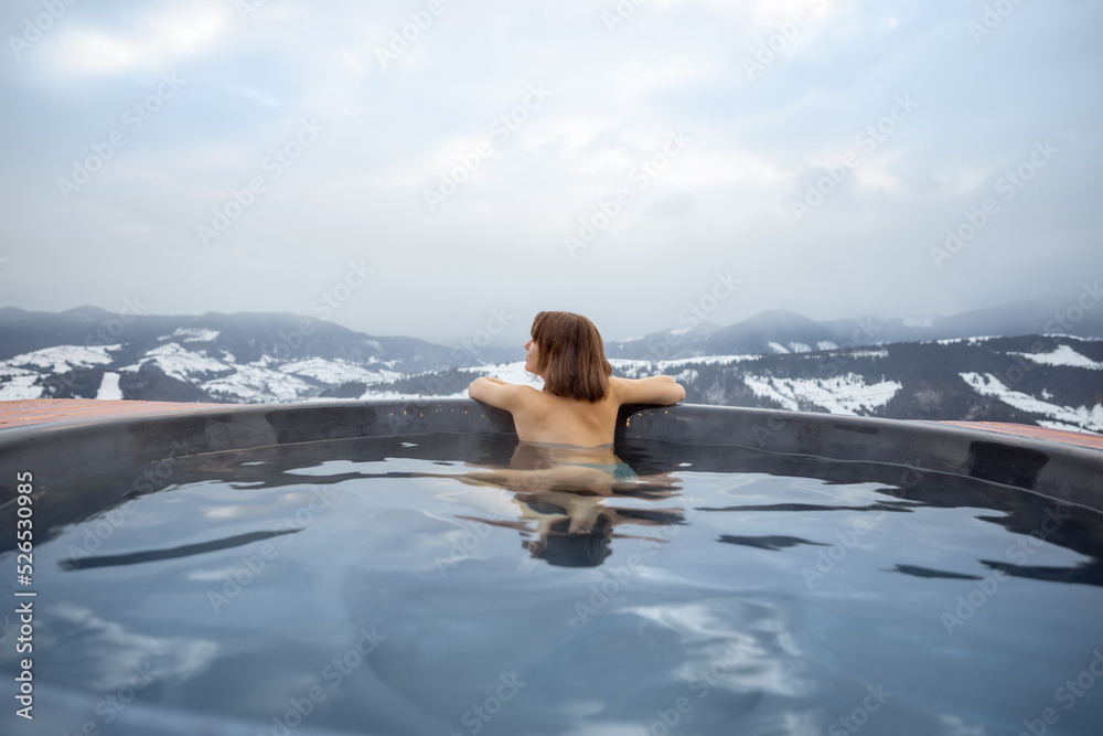 年轻女子冬天在山上的热水浴缸里洗澡。在热水浴缸里休息和恢复的概念