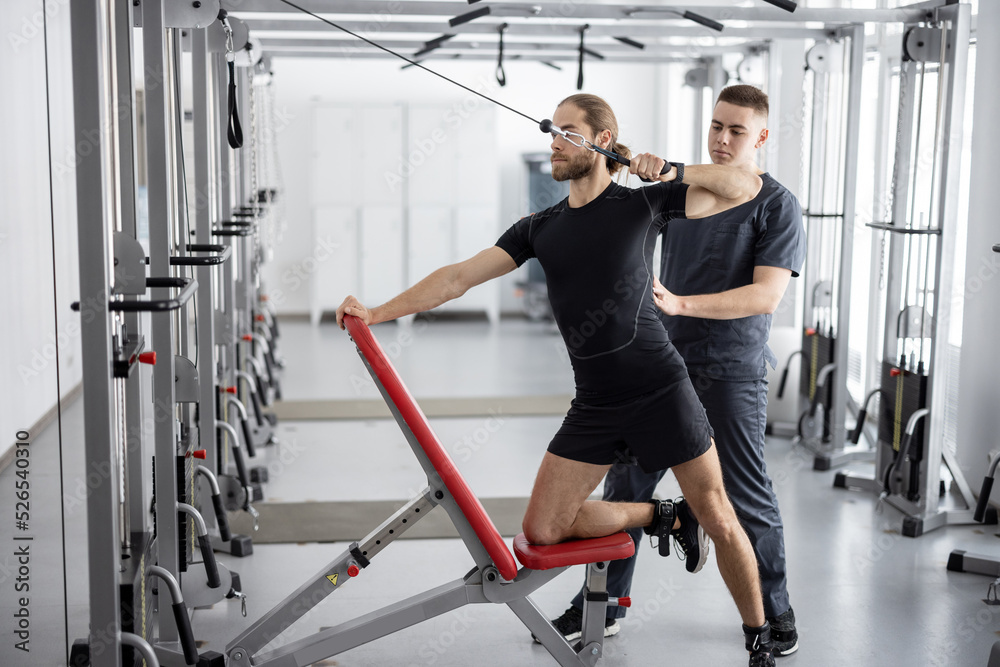 Man doing exercises on decompression simulators with the help of rehabilitation specialist. Concept 