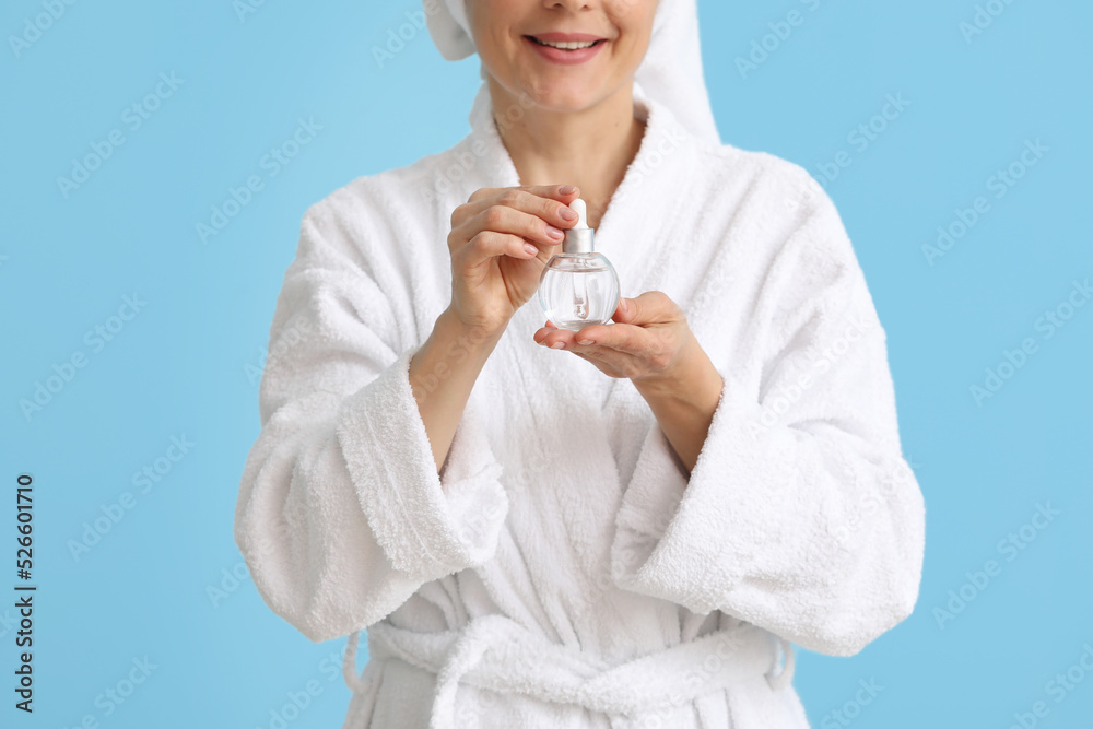 Mature woman with cosmetic serum on blue background