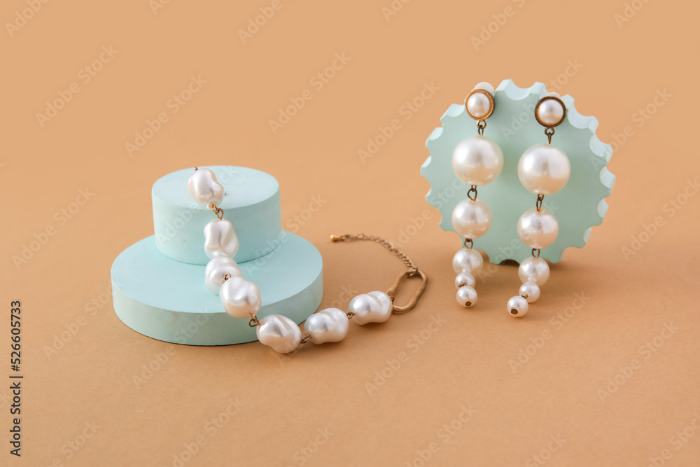 Showcase pedestals with elegant pearl jewelry on beige background