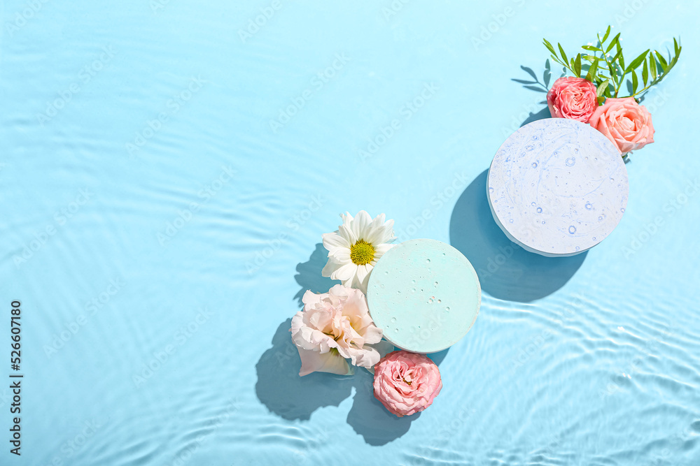 Beautiful composition with decorative stands and flowers in water against blue background