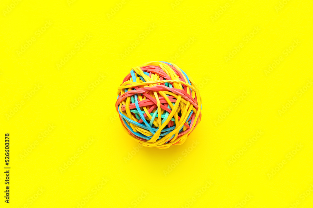 Colorful rubber band ball on yellow background