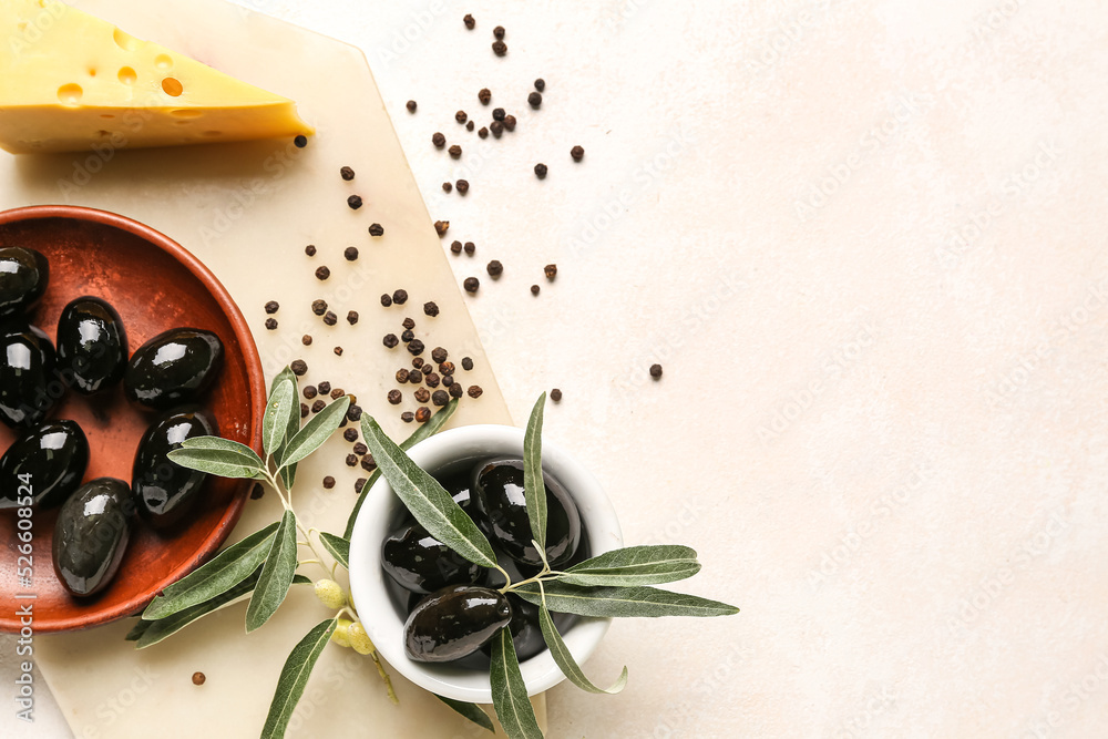 Bowls with tasty black olives, cheese and peppercorns on light background