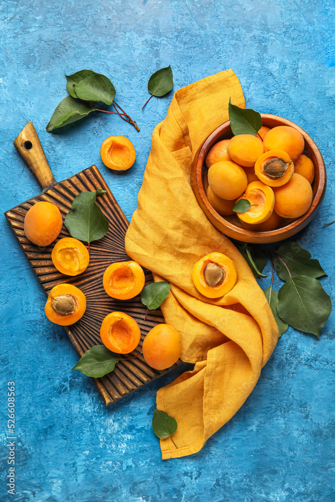 Composition with bowl of ripe apricots and leaves on color background