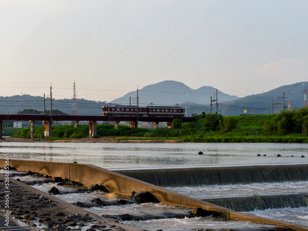 朝焼けの大和川を渡る近鉄道明寺線の電車
