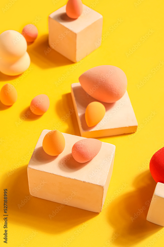 Makeup sponges with decor on yellow background